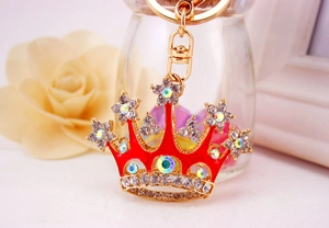 Macro shot of red crystal crown keychain with sparkling rhinestones and gold-tone metal hooks