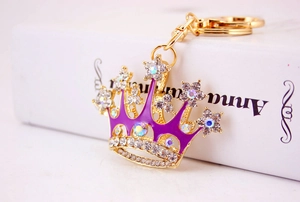 Detailed macro view of a golden metal crown keychain with purple rhinestones on a book