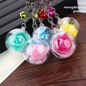 Close-up of five colorful rose pendant keychains with bells on a display tray