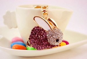 Détail d'un porte-clés lapin doré avec strass violets et blancs sur une assiette blanche