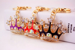 Close-up of crown-shaped keychains in purple, red, and black with sparkling crystals