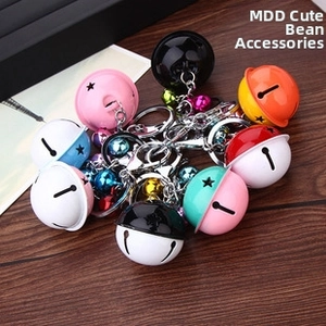 Detailed view of colorful star-cutout metal bell keychains on a rustic wood surface