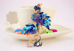 Détail d'un pendentif flamant rose serti de strass bleus sur base en métal doré