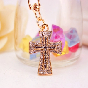 Golden cross keychain with sparkling crystals and lobster clasp on blurred background