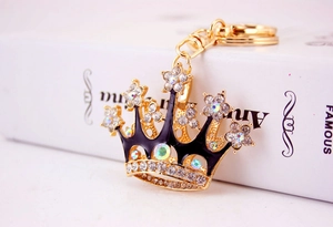 Macro view of golden crown keychain with sparkling crystals and black enamel finish