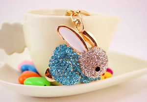 Détail d'un porte-clés lapin doré avec strass roses et bleus sur une soucoupe blanche