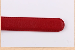 Detail of red lychee grain leather belt strap with fine stitching and rounded tip finish