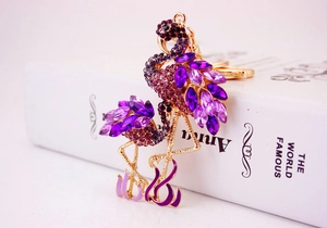 Détail de pendentifs flamants roses dorés avec cristaux violets et strass brillants
