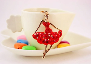 Detail of ballerina keychain with red rhinestones on a white porcelain cup edge