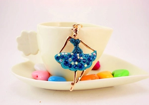 Close-up of ballet dancer pendant with blue rhinestones on a gold alloy metal keychain