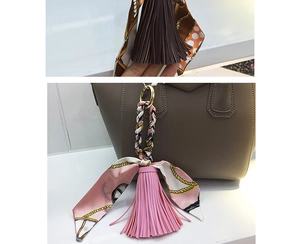 Dettaglio del ciondolo a nappa in pelle e foulard di seta su una borsa a mano beige chic