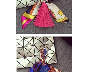Dettaglio di nappe in pelle e foulard di seta su borse con motivi geometrici