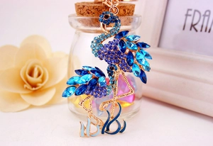 Détail du porte-clés flamant rose avec strass bleus et finition en métal doré