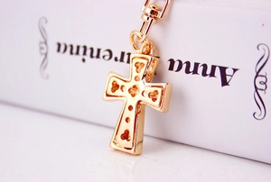 Detail shot of a golden hollow cross keychain pendant with intricate metal engravings