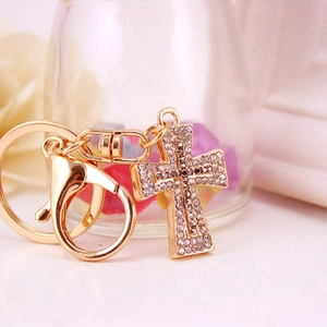 Golden sparkling crystal cross keychain with clear rhinestones on elegant background