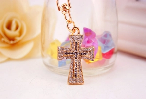 Detailed view of golden cross keychain with sparkling white and blue rhinestones