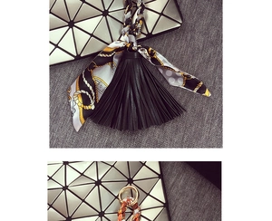Dettaglio del ciondolo per borsa con nappa in pelle nera e foulard in seta leopardata