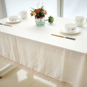 Macro detail of beige cotton linen tablecloth with elegant lace edges on a wooden table