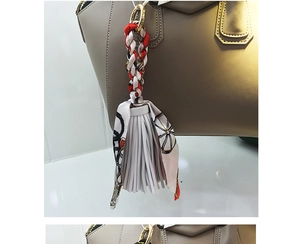 Dettaglio charm borsa intrecciato rosso e bianco con foulard motivo carrozza retrò