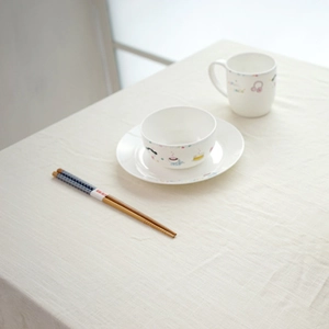 Close-up of children ceramic tableware set on natural beige linen tablecloth