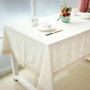 Close-up of white linen tablecloth with elegant lace trim edge and soft natural texture