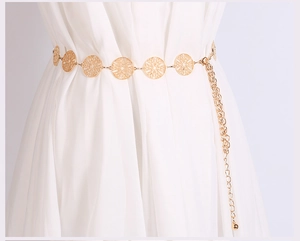Close-up of golden metal waist chain with hollow round charms on a white dress
