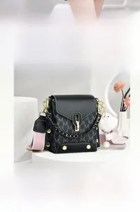 Detail of black M-embossed crossbody bag with golden twist lock on white stone podium