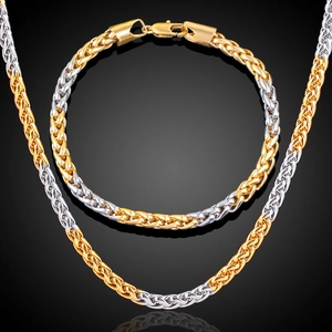 Detail of two-tone gold and silver wheat chain necklace and bracelet set on black background
