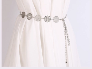 Detail of silver metal waist chain with hollowed circles on a white dress