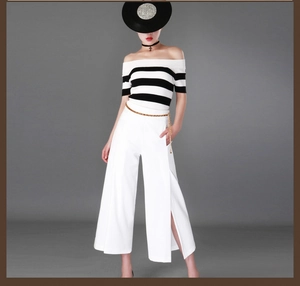 Detail showing an adjustable gold metal waist chain paired with white high-waist trousers