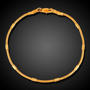 18K gold-plated snake bone chain necklace with cylindrical beads on black background