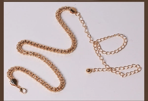 Close-up of golden metal corn chain with lobster clasp and ball pendant detail