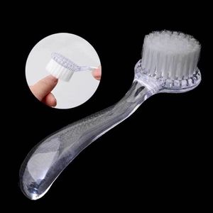 Détail des poils blancs doux et du manche ergonomique transparent de la brosse à ongles