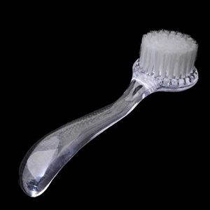Détail d'une brosse à ongles à long manche en plastique transparent avec poils blancs doux