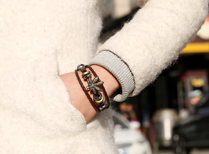 Dettaglio del bracciale vintage in pelle intrecciata con ciondolo foglia di acero bronzo