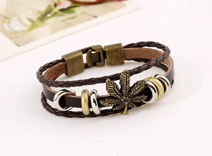Dettaglio del bracciale vintage in pelle intrecciata con ciondolo a foglia d'acero