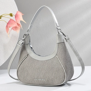 Detail of grey crescent handbag featuring vertical pleated texture and silver hardware