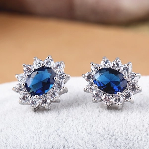 Macro shot of silver stud earrings with blue oval zircon and sparkling white crystals