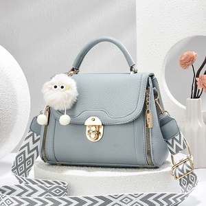 Light blue lychee pattern handbag with wide geometric strap and plush pendant accessory
