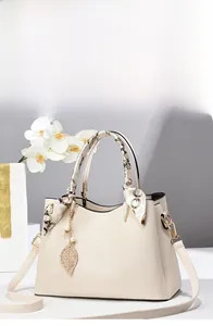 Close-up of cream leather handbag with printed silk scarf handle and gold leaf charm detail