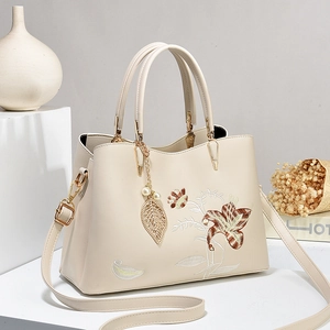 Sac à main crème avec broderie florale et pendentif en perles sur fond blanc élégant