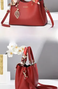 Detail of red lychee grain leather handbag with gold leaf charm and printed silk scarf