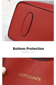 Detail of red pebbled leather handbag featuring gold logo and protective base studs