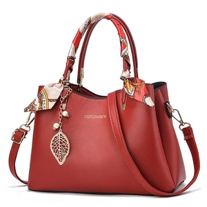Elegant red pebbled leather handbag for women featuring a silk scarf handle and pearl charm