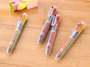 Close-up of four transparent 6-color ballpoint pens on a rustic wooden desk