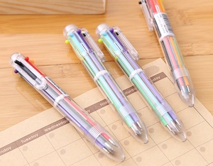 Detail of 4 transparent 6-color retractable ballpoint pens on a wooden desktop