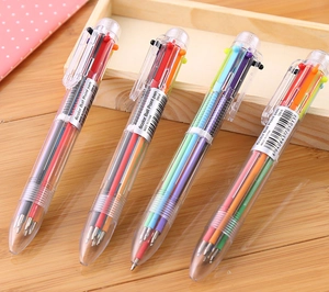 Detail of 6-color ballpoint pens with transparent barrels on a wooden desk and notebook