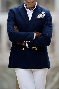Detail of navy double-breasted blazer with patterned ascot tie and brown leather gloves