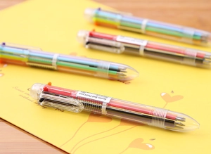 Close-up of four transparent 6-color ballpoint pens with visible multi-colored refills