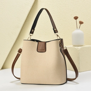 Straw woven bucket bag with dark brown leather trim and adjustable crossbody strap
